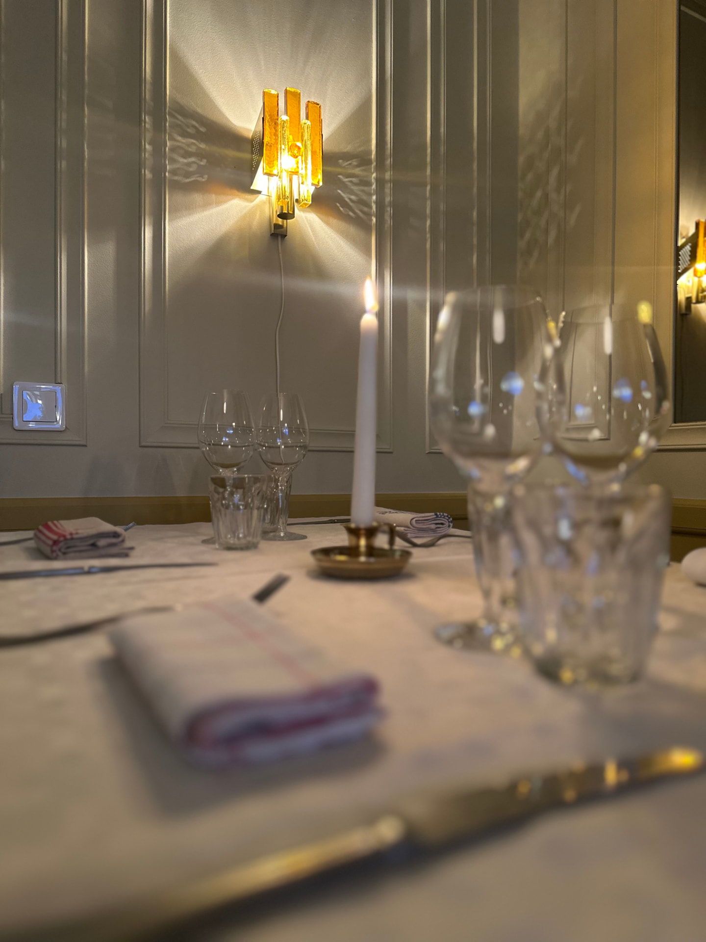 Närbild på dukning med servett, glas och vägglampa